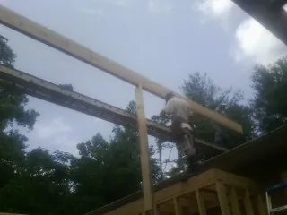 Carpenter setting a ridge beam over a new addition frame — Ice Dam Removal by Roofing Brothers in Comer