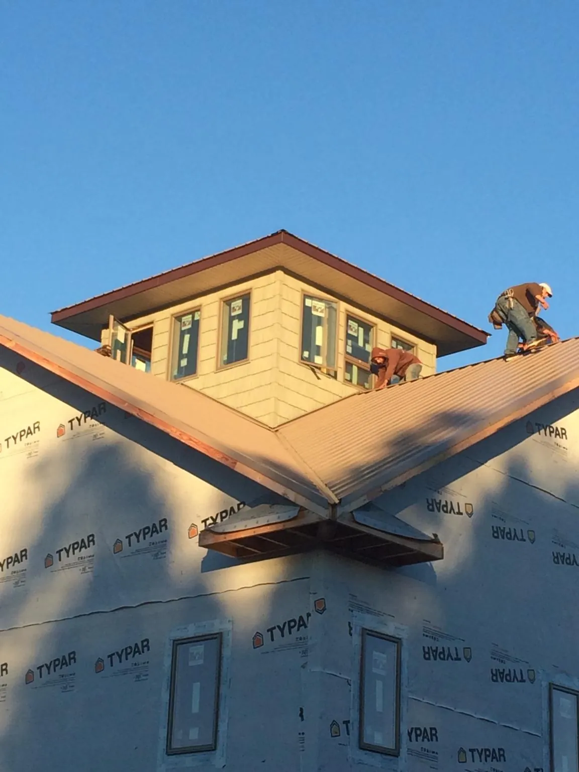 Roofers working around a rooftop cupola on a new metal roof at sunset — Roof Waterproofing in Comer by Roofing Brothers